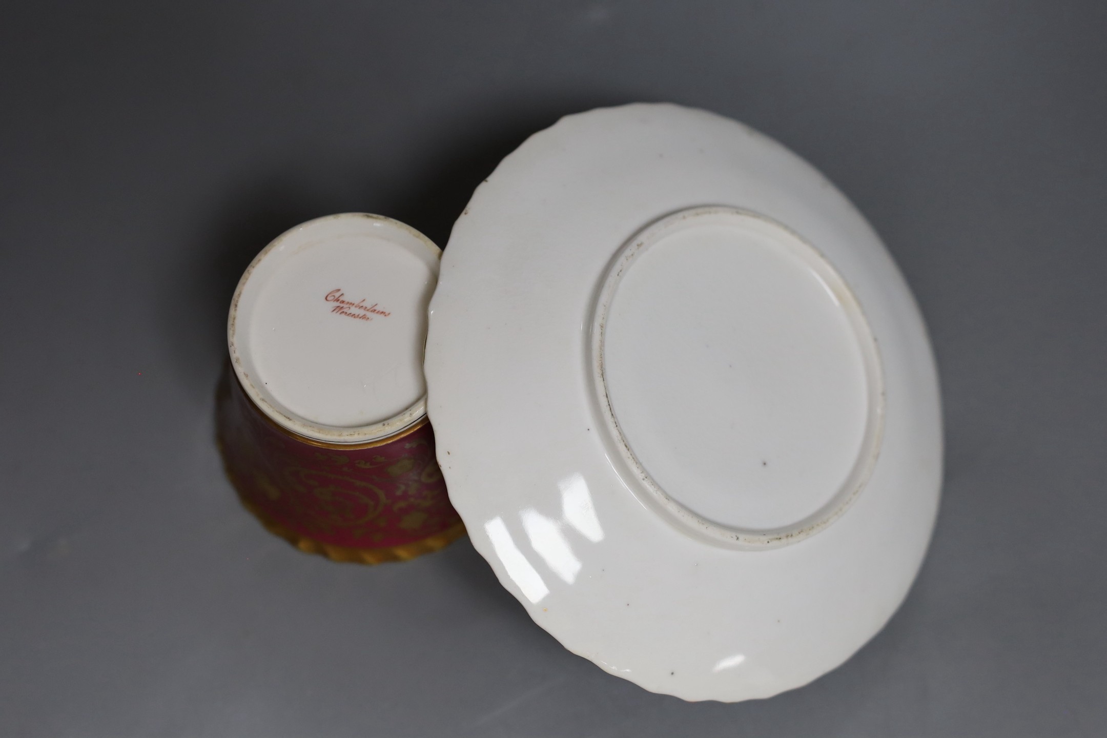A Chamberlains Worcester superb coffee cup and saucer with crinson ground and elaborate gilding the saucer painted with flowers, the cup painted with flowers in and out, script mark in red to cup